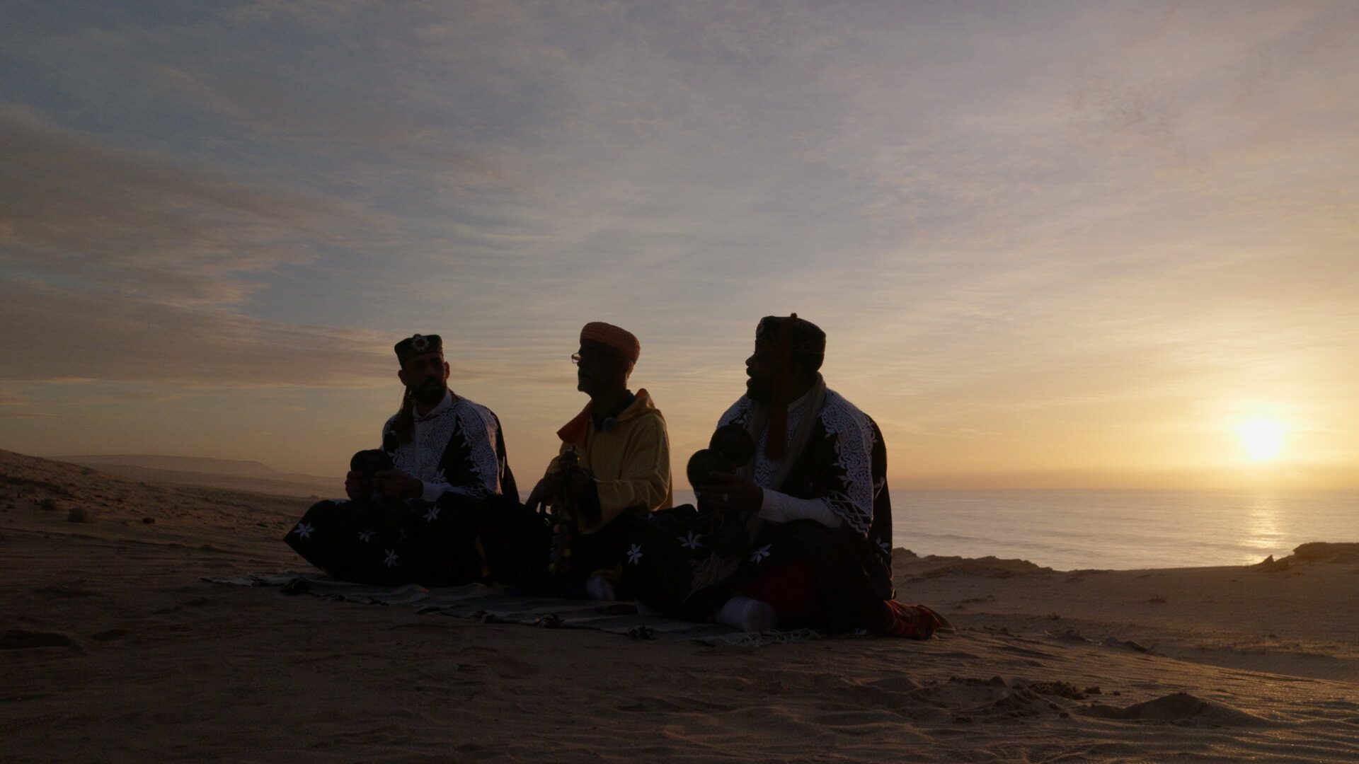 Musicians seated in the desert at dusk — El Guayota documentary